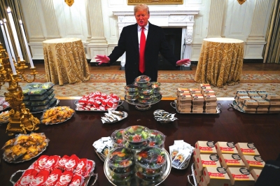1月14日，美国总统特朗普站在摆满快餐的白宫国宴厅餐桌前。
