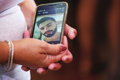 一名失踪人员家属接受媒体采访，手机上显示她失踪儿子的照片。　□新华社照片