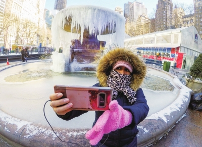 1月31日，在美国纽约布赖恩特公园，一名女子在结冰的喷泉前拍照。　□新华社照片